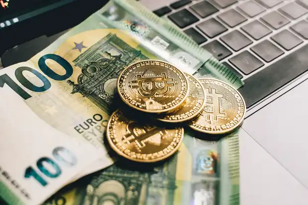 Euro notes and a laptop showing a chart on a desk