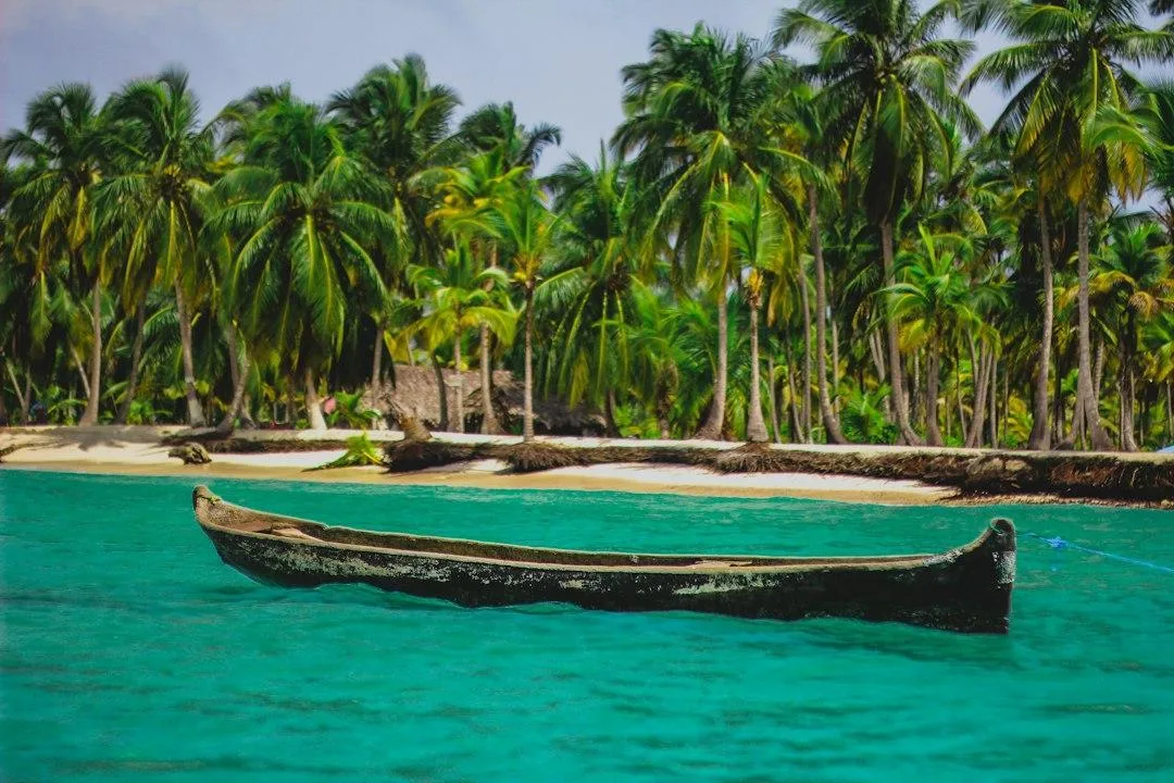 A wooden dugout canoe moored off a palm-lined beach in Panama's San Blas islands