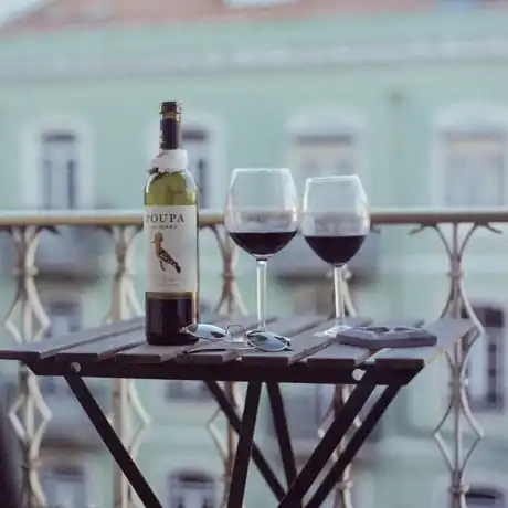 A bottle of Portuguese red and two glasses on a Lisbon balcony at dusk