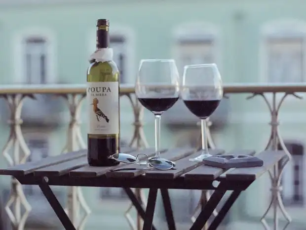 A bottle of Portuguese red and two glasses on a Lisbon balcony at dusk