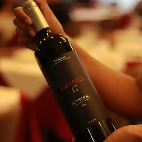 A bottle of Douro Superior red wine held at a tasting table