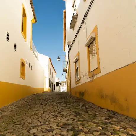 A cobbled street between whitewashed houses trimmed in ochre