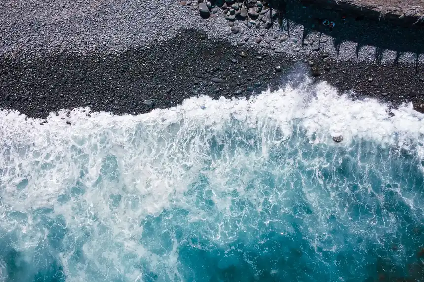 Black volcanic shore and clear Atlantic water seen from directly above