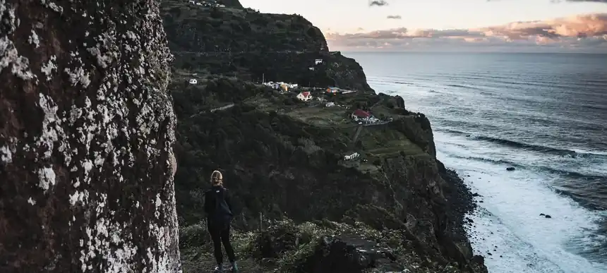 A walker on a cliff path above the north coast of Madeira at dusk
