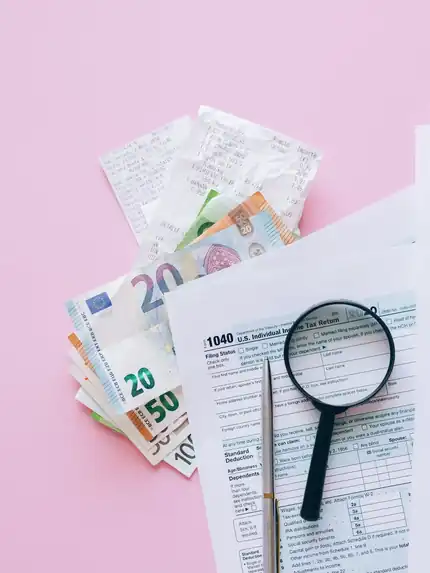 Tax paperwork, euro notes and a magnifying glass on a desk