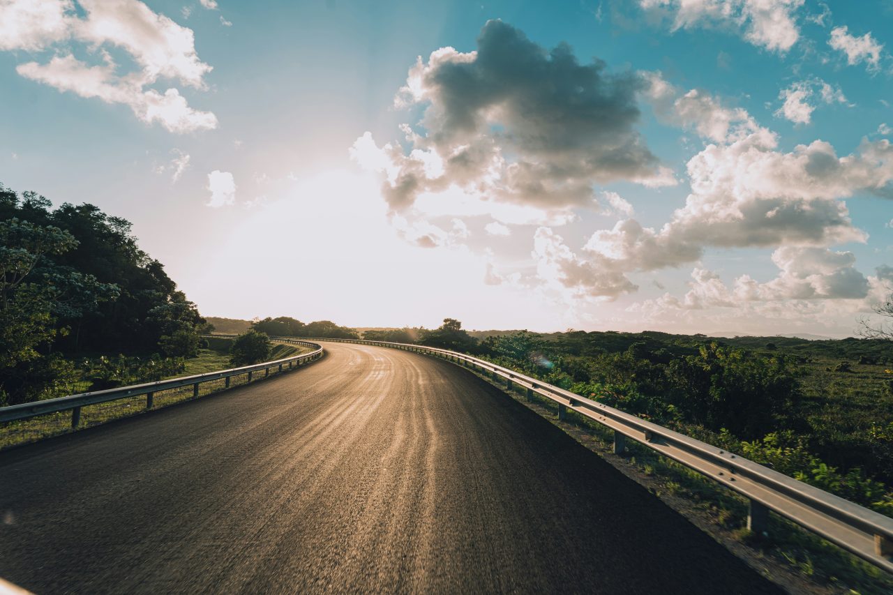 A highway curving through green countryside in the Dominican Republic at sunset